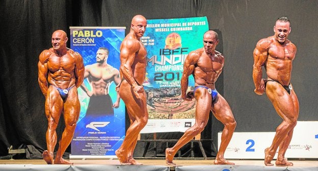 Cuatro culturistas durante la prueba que cerró el Mundial celebrado el sábado en el Pabellón Central de Cartagena./J. M. Rodríguez / AGM
