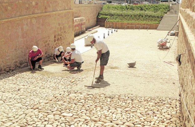 Obreros dando los últimos retoques al suelo de cantos rodados el pasado viernes.