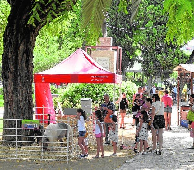Familias y niños pasean junto a los ponis de la feria.