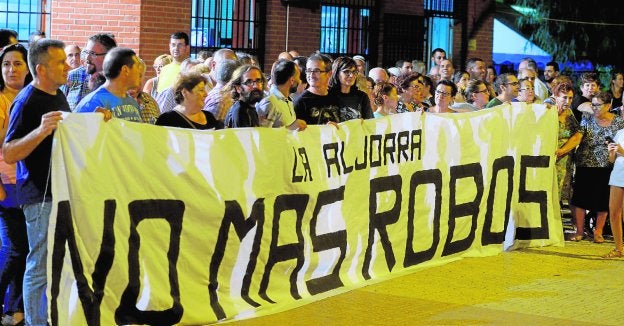 Vecinos y víctimas de la última oleada de robos, anoche, portando una pancarta, a las puertas del local social de La Aljorra.