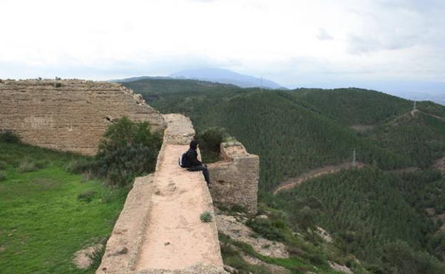 Un senderista descansa sobre una de las murallas del Castillo del Puerto (también llamado de La Asomada), que domina las laderas arboladas del Parque Regional El Valle-Carrascoy./