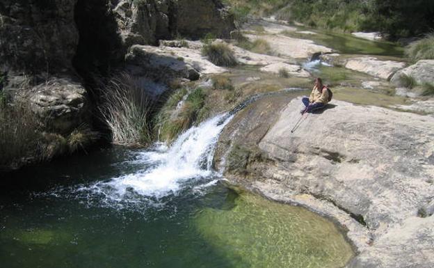Un senderista se relaja junto al Pozo de los Azules, que se abre en el cauce del Alhárabe a medio camino entre La Risca y La Puerta./
