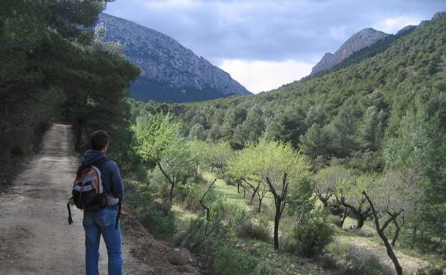 Un senderista hace un alto en el camino. Al fondo, el Morrón Chico y las cumbres del Valle de Leyva./