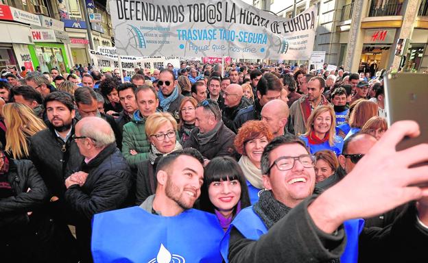 Tres jóvenes se hacen un selfi ante la mirada de varios miembros del Gobierno regional y del PP murciano; entre ellos, el presidente Fernando López Miras./Nacho García / AGM