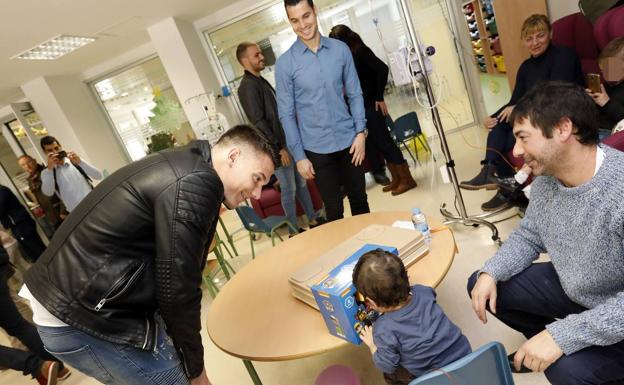 Los futbolistas entregan un juguete a uno de los niños hospitalizados./EDU BOTELLA/ AGM