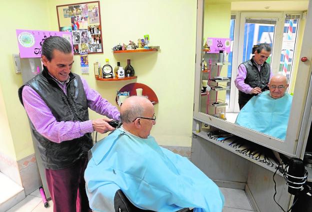 José Carlos García, en su peluquería, le corta el pelo a un cliente./Antonio Gil / AGM