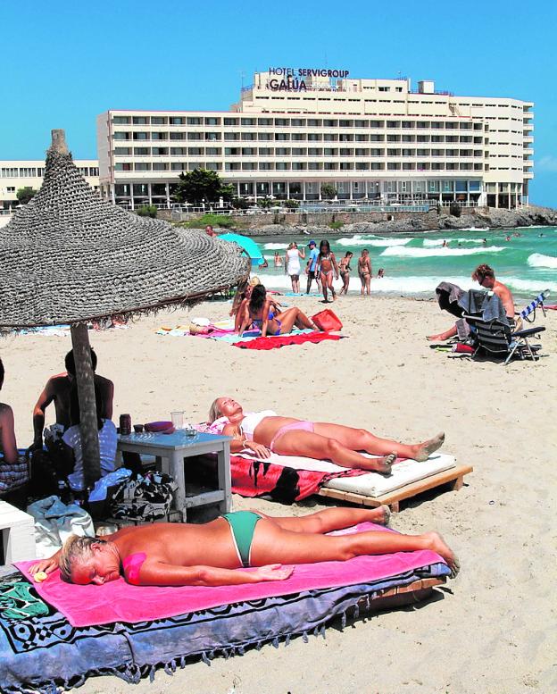 Turistas en una playa de La Manga, con el hotel Galúa al fondo. / Pablo Sánchez / AGM