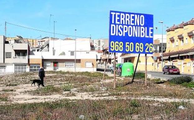 Un hombre cruza con su perro el solar de Finca Berizo, cuya promoción urbanística se demora por la falta de amparo legal. / pablo sánchez / agm