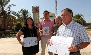 Sandra Martínez, Luis González, el Padre Jerónimo, y Juan Tomás con el cartel de las fiestas delante del Santuario cubierto de andamios. :: P. A. / AGM/