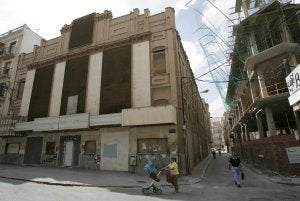 Una mujer pasa con un carricoche pasa frente al antiguo Cine Central, a la izquierda, y el edificio en construcción en la calle Don Roque. :: J. M. RODRÍGUEZ / AGM/