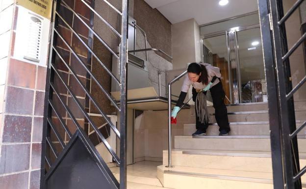 Una mujer limpia los pasamanos del portal de un edificio en plena crisis del coronavirus./J.P.