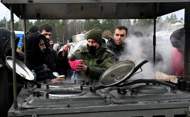 Immigrants on the border between Belarus and Poland in front of a field kitchen to collect food.