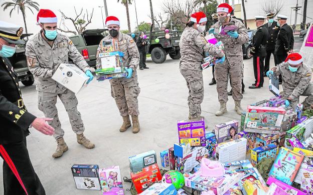 Six soldiers pile the toys that they took in their vehicles to the Sports Palace. 