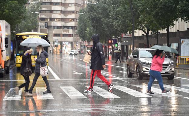 Several people walk through Murcia on a rainy day, in a file image.