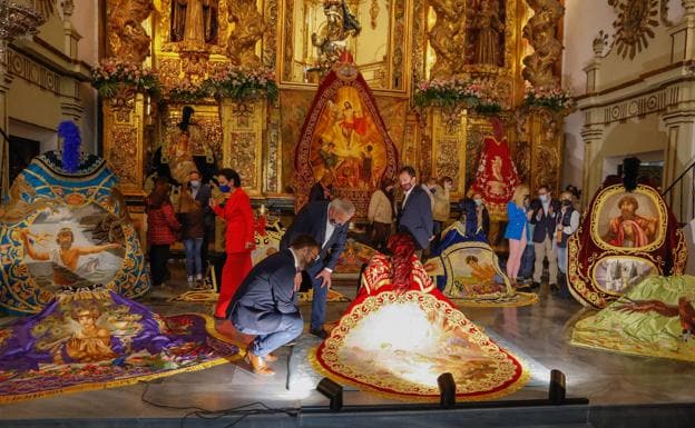 The mayor, crouching, the blue president, at his side, and the deputy mayor, standing, observe one of the mantles of El Triunfo del Cristianismo in the church of San Francisco. 