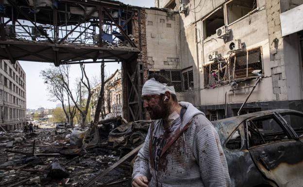 A wounded man walks through the ruins of Kharkiv.