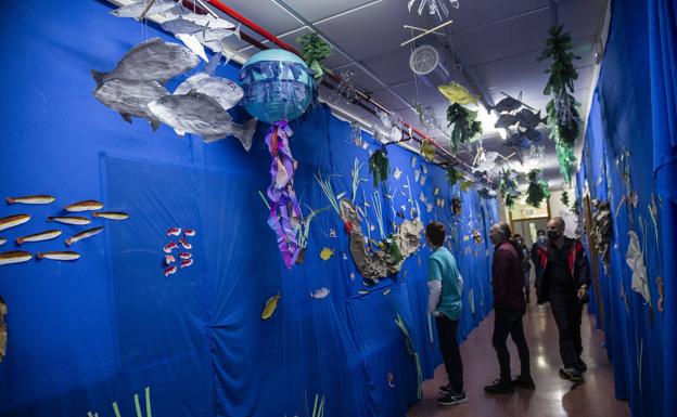 A group of students and teachers in a corridor decorated with motifs from the Mar Menor. 