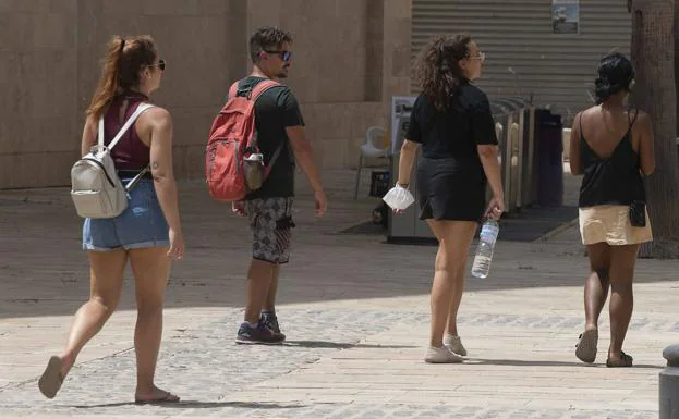 Several people walking down the street in shorts. 