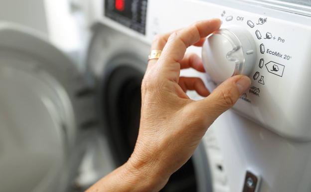 A person adjusting his washing machine. 