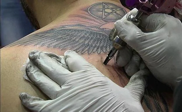 A tattoo artist performs a tattoo. 