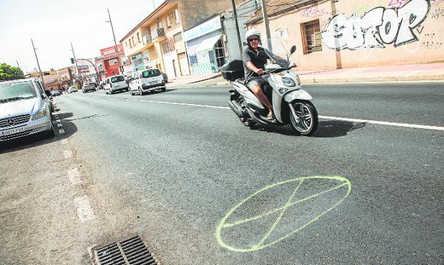 A man is riding a motorcycle along the section of Peroniño street where potholes have appeared, marked for a few days. 
