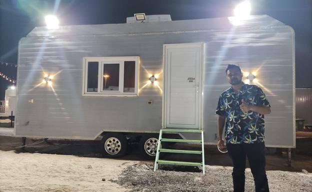 Arkadash poses next to the caravan in which he spends his honeymoon.