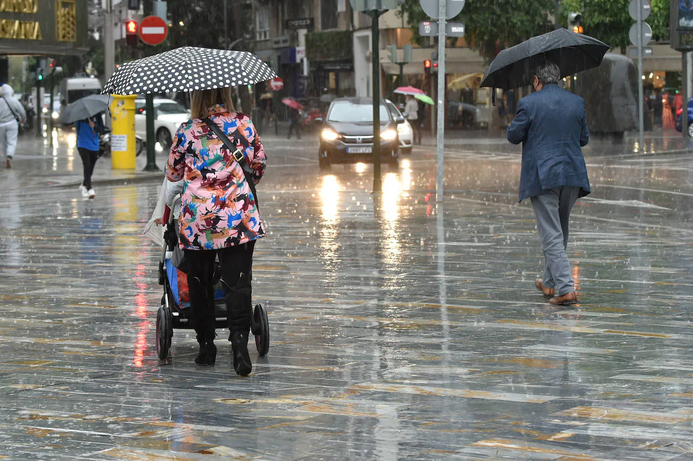 Two people walk with umbrellas in the rain in Murcia. 