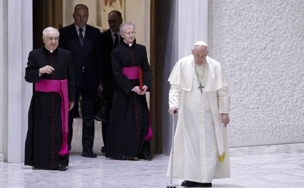 The Pope, leaning on a cane, goes to deliver his speech to the Curia.