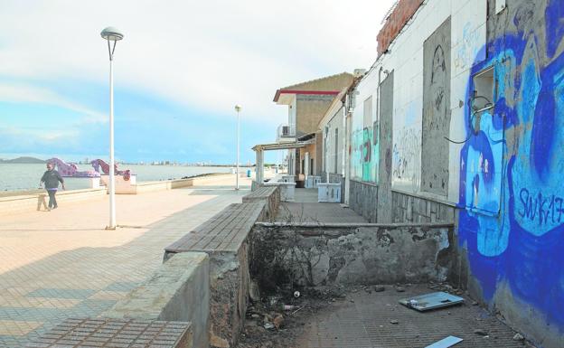 A resident of Los Nietos walks along the seafront, next to one of the many boarded-up houses in this town. 