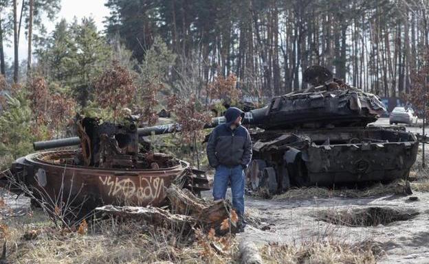 A man looks at destroyed Russian armored vehicles on the outskirts of kyiv